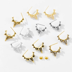 Macro shot of geometric crown spike earrings in gold and silver with zircon inlays