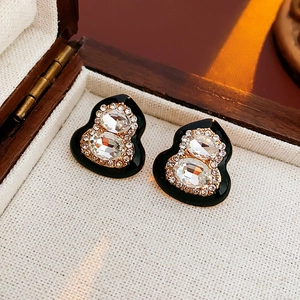 Macro detail of vintage black and gold gourd earrings with sparkling crystal accents