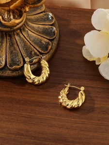 Dettaglio di orecchini a cerchio intrecciati in acciaio placcato oro 18k su base vintage