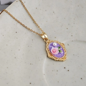 Detalle de colgante ovalado vintage con esmalte morado y rosa 3D en cadena oro
