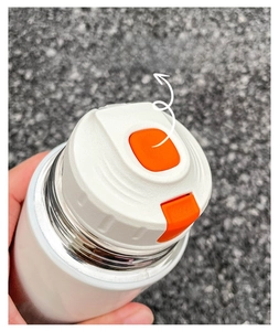Close-up of the white vacuum flask featuring an orange push-button lid for easy opening