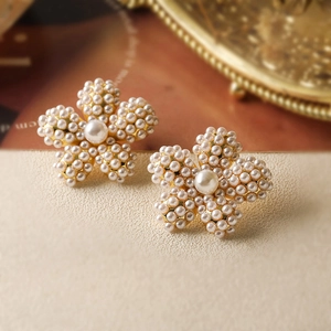 Orecchini a perno a fiore con perle stile lusso francese su sfondo beige testurizzato