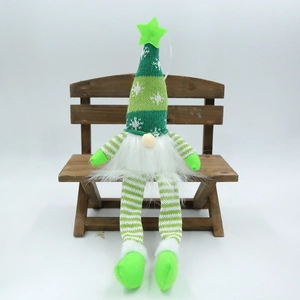 Détail d'un gnome de Noël avec bonnet tricoté à rayures vertes et blanches sur banc