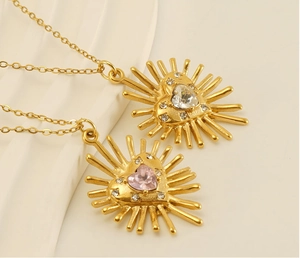 Gros plan de pendentifs cœur soleil en or avec pierres de zircon sur fines chaînes dorées