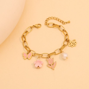 Detail of golden bracelet featuring pink tulip, butterfly, and flower pendants with pearls