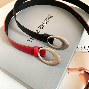 Detailed close-up of slim black and red leather belts with matte silver oval buckles