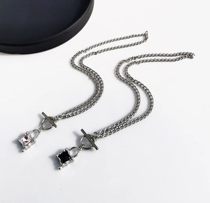 Macro detail of OT buckle necklaces with pink and black square gemstone lock pendants