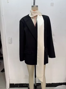 Vue détaillée d'un blazer noir avec écharpe blanche contrastée sur un mannequin de mode