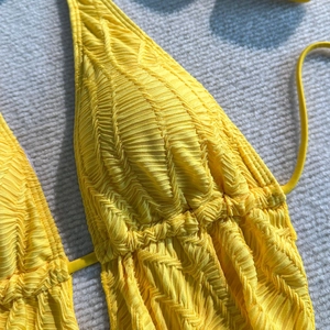 Nahaufnahme des hellgelben Bikini-Tops mit detaillierter Faltenstruktur und Bändern