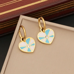 Goldene Herzohrringe mit blau-weißem Emaille und Strass auf einer beigen Schmuckschatulle