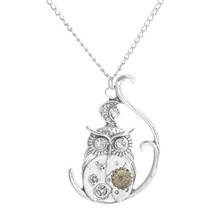 Detail of owl pendant necklace with steampunk gears and crystal eyes in silver finish