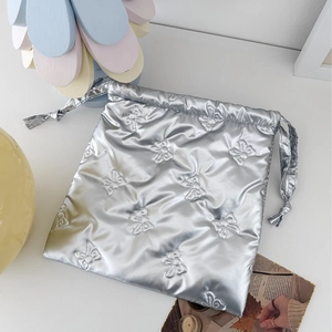 Metallic silver drawstring pouch with embossed bow texture for cosmetic storage