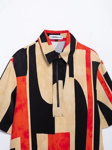 Detail of half-zipper neckline and BBWM brand label on red geometric print shirt