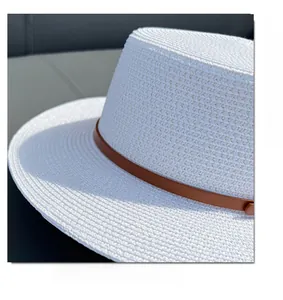 Detail of white straw boater hat featuring a brown leather decorative band and texture