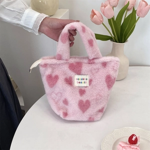 Close-up of pink plush handbag featuring heart patterns and soft faux fur texture
