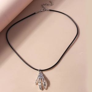 Detailed view of silver skeleton hand pendant with vintage spider web design on black cord