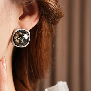 Gros plan sur des boucles d'oreilles carrées avec texture étoilée et feuilles d'or en argent