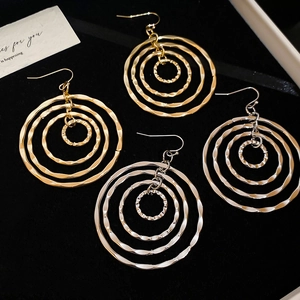 Macro view of layered geometric circular earrings in gold and silver textured metal
