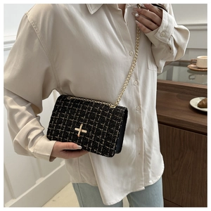 Détail du sac bandoulière en tweed noir avec chaîne dorée et fermoir rotatif en métal