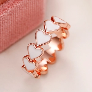 Gros plan d'un anneau en forme de cœur or rose avec incrustation d'émail blanc pur