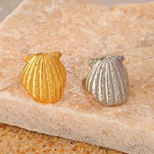 Golden and silver shell shaped rings with realistic textures on a natural stone base