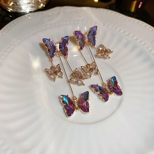 Detail of silver needle butterfly tassel earrings with purple crystals on a white plate