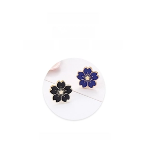 Detail of blue and black cherry blossom enamel brooches with golden pistil accents