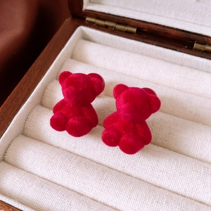 Macro shot of 3D dark red flocked bear stud earrings resting in a wooden jewelry box
