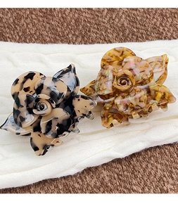 Detailed view of 3D floral acetate hair claws in dark tortoise and amber patterns
