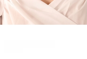 Detail view of the elegant wrap-style neckline on this light beige woven fabric garment