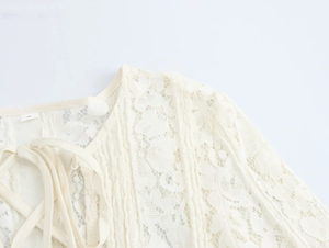 Detailed close-up of cream lace knit bodice with elegant shoulder tie-up design