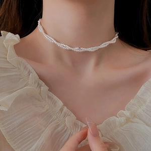 Dettaglio della collana di perle a doppio strato con diamante centrale su una modella