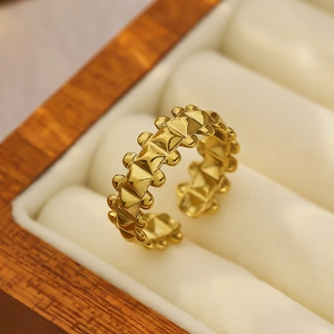 Macro shot of gold geometric rivet ring with studded details on white velvet display