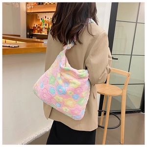 Pink plush tote bag with colorful flower patterns shown on a female model in a cafe setting