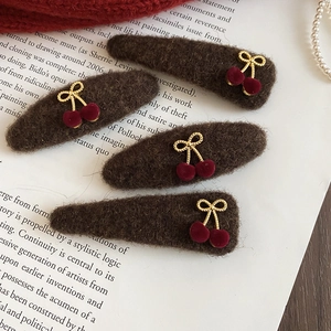 Detail of four brown plush hair clips with cherry charms on a vintage book background