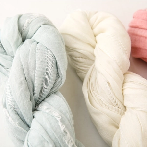 Macro texture of soft hollow pleated scarves in pastel blue, cream and pink with fringe