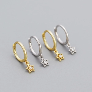 Detail of gold and silver star earrings with brilliant zircon stones on grey background