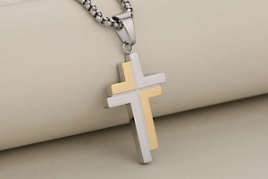 Detailed close-up of a two-tone silver and gold stainless steel cross pendant necklace