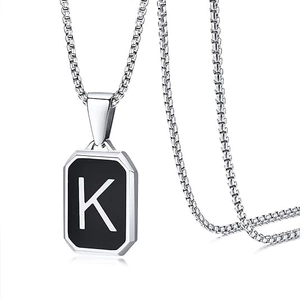 Detailed close-up of a silver chain with a black rectangular pendant featuring letter K