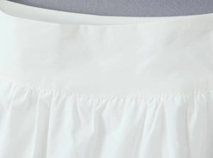 Detail of precise stitching and smooth fabric texture on the white high waist skirt