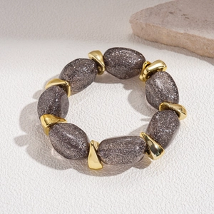 Detail of vintage acrylic oval beads and golden geometric spacers on a beaded bracelet