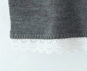 Gros plan sur un tricot gris avec une bordure délicate en dentelle blanche sur le bas