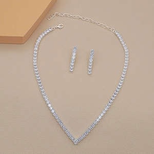 Flat lay of a silver bridal jewelry set with rectangular zircons on beige texture