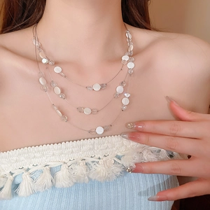 Gros plan d'un collier multicouche en nacre et cristal sur le cou d'un mannequin