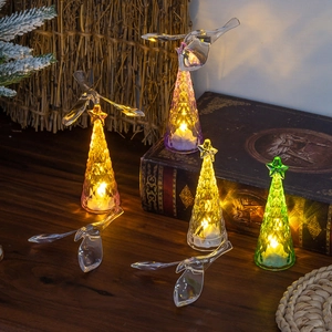 Close-up of glowing crystal Christmas tree lights and transparent bird ornaments on desk