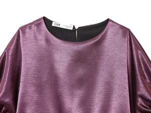 Détail de l'encolure en V satinée élégante et étiquette de marque sur un chemisier violet