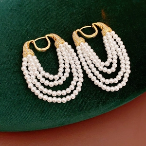Macro detail of vintage multi-layer pearl drop earrings with zircon gold plating