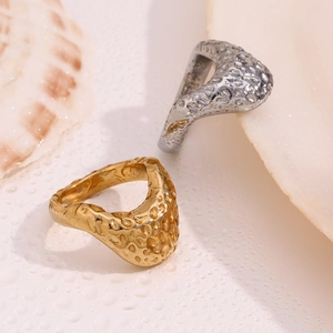 Detail of 18K gold and silver rings featuring unique hammered lava textures on beige background