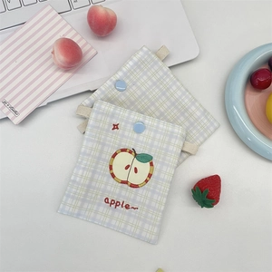 Detail of embroidered apple pattern on blue plaid fabric storage pouch with button