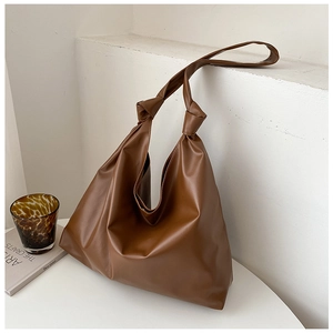 Detail of soft brown leather tote bag with knotted shoulder strap in minimalist setting